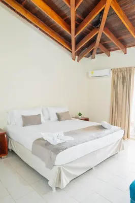 a bedroom with a large white bed with wooden ceilings at Hotel Playa Palmeras Cartagena - Vía al Mar in Cartagena de Indias