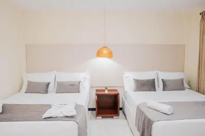 a room with two beds and a nightstand between them at Hotel Playa Palmeras Cartagena - Vía al Mar in Cartagena de Indias