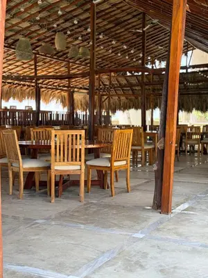 a group of wooden tables and chairs in a pavilion at Hotel Playa Palmeras Cartagena - Vía al Mar in Cartagena de Indias
