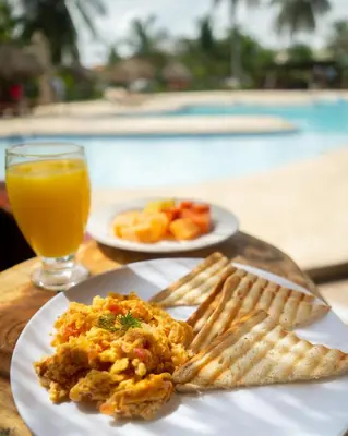 a table with a plate of food and a glass of orange juice at Hotel Playa Palmeras Cartagena - Vía al Mar in Cartagena de Indias