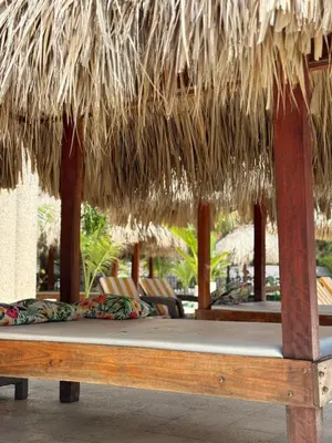 a bed under a straw umbrella at a resort at Hotel Playa Palmeras Cartagena - Vía al Mar in Cartagena de Indias