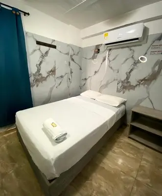 a bedroom with a white bed with a wall at Hotel Rancho Grande in Barranquilla