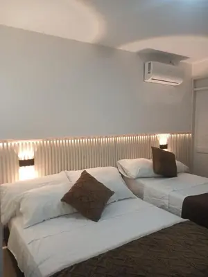 a bedroom with two beds with white sheets and brown pillows at Hotel Palma Real Cartagena in Cartagena de Indias
