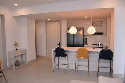 a kitchen with a bar with chairs and a counter top at Lujoso Penthouse - Vista al Mar - Playa Privada in Cartagena de Indias