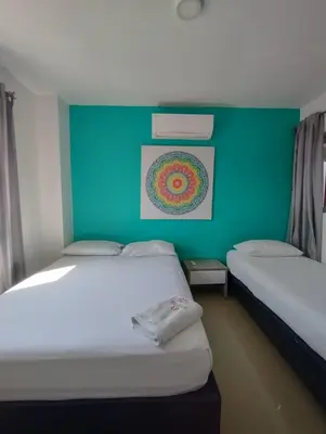 two beds in a room with a green wall at HOTEL BELLAMAR in Cartagena de Indias