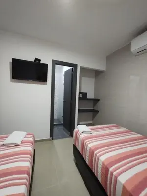 a room with two beds and a flat screen tv at HOTEL BELLAMAR in Cartagena de Indias