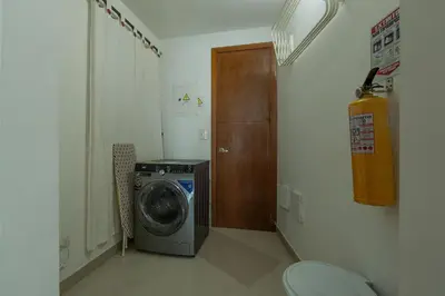 a bathroom with a washing machine and a wooden door at Un espacio sofisticado en medio de El Laguito Edificio Poseidon del Caribe in Cartagena de Indias