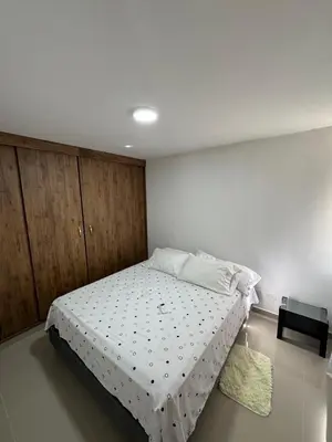 a bedroom with a bed with white sheets and a table at Apto amoblado en Alameda del Río in Barranquilla