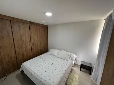 a bedroom with a bed and wooden cabinets at Apto amoblado en Alameda del Río in Barranquilla