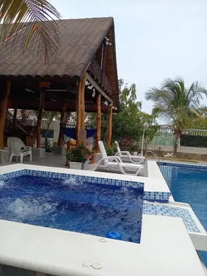 a pool at a resort with two chairs and a gazebo at Sharick Beach House in Tubará