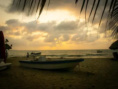 a boat sitting on a beach with the ocean at Mithival Beach Rincón del Mar in Rincón