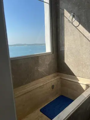 a bathroom with a shower with a window and a blue mat at 360° Sea View Penthouse 17° floor, Cartagena in Cartagena de Indias