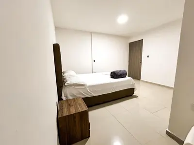 a small bedroom with a bed and a wooden bench at Hotel & Restaurante Oasis CTG in Cartagena de Indias