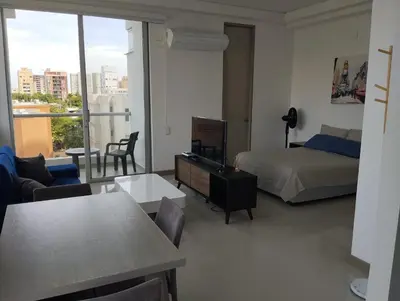 a bedroom with a bed and a living room with a view at Apartaestudio Jacuzzi Centro Comercial Gimnasio ALTOPRADO in Barranquilla