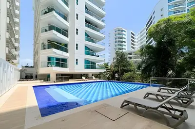 a swimming pool with two chairs and a building at Apartamento 2 Dormitorios Morros. Salida playa in Cartagena de Indias