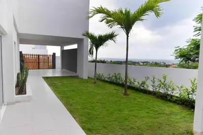 a white house with a green lawn and palm trees at Espectacular casa en oferta con piscina privada y vista al mar in Carretal