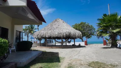 a straw hut on a beach with the ocean at Cabaña La Pereztroica 2 in Puerto Viejo
