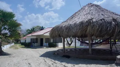 a straw hut on the beach next to a building at Cabaña La Pereztroica 1 in Coveñitas