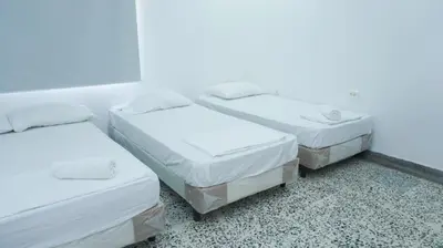 three beds in a room with white walls at Cabaña La Pereztroica 1 in Coveñitas