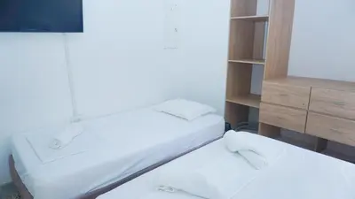 two beds in a room with a tv and a cabinet at Cabaña La Pereztroica 3 in Coveñitas