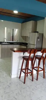 a kitchen with a counter with two chairs and a refrigerator at Villa Carolina SM in Santa Marta