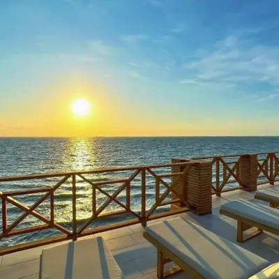 a deck with benches and the ocean at sunset at SUITE OCEAN VIEW - Playa in Tolú