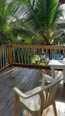 a wooden deck with a chair and a table and a palm tree at KAZA Balcones in Santa Veronica