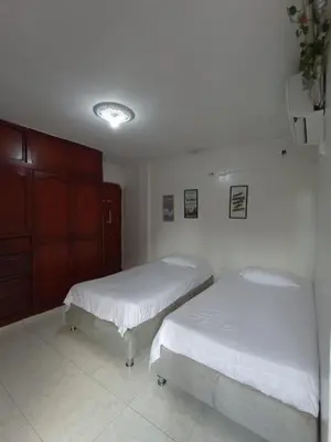 two beds in a room with white walls at Hostal Miami Beach in Cartagena de Indias