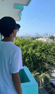 a man standing on a balcony looking out at the city at Hostal Miami Beach in Cartagena de Indias