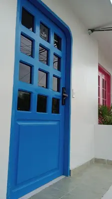 a blue door on a white wall with a window at Hostal Miami Beach in Cartagena de Indias