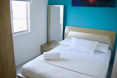 a bedroom with a white bed and a blue wall at Great location close to airport in Cartagena de Indias