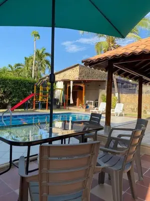 a table and chairs with an umbrella next to a pool at Palma House - Cabaña con piscina in Tubará