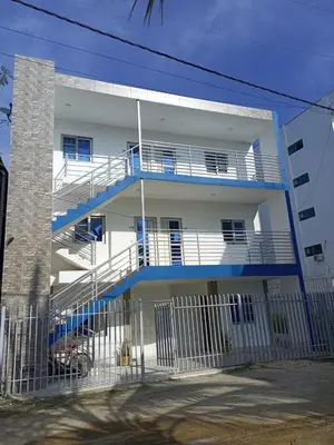 a white apartment building with blue balconies and a fence at Apartamentos Mi Reserva OK - Miraluna in Coveñas