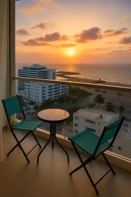 a balcony with two chairs and a table and a sunset at Exclusivo apartamento en Cielo Mar-playa las Americas, con maravillosas vistas del atardecer de Cartagena in Cartagena de Indias