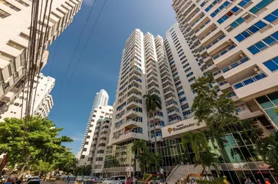a tall white building with palm trees in front of it at Apartamento Lindo en cartagena el laguito bocagrande con vista al mar in Cartagena de Indias