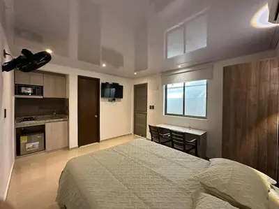 a bedroom with a bed and a desk and a kitchen at Apartaestudio 2 en Barranquilla in Barranquilla