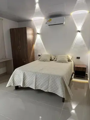 a bedroom with a bed with white sheets and lights at Apartaestudio 2 en Barranquilla in Barranquilla