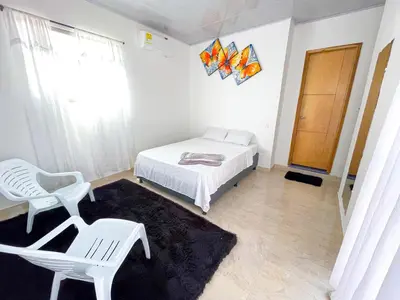 a bedroom with a bed and a chair and a window at Apartamento Doña Flor in Coveñas