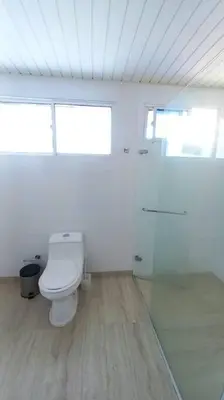 a white bathroom with a toilet and two windows at Penthouse en Cartagena in Cartagena de Indias