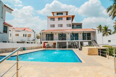 a house with a swimming pool in front of a building at Hotel Caribe Coveñas in Coveñas