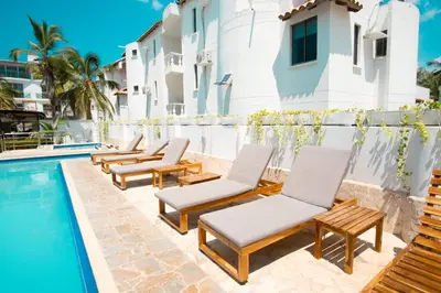 a row of chaise lounge chairs next to a swimming pool at Hotel Caribe Coveñas in Coveñas