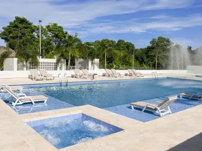 a swimming pool with lounge chairs and a fountain at Ciela Hotel in Coveñas