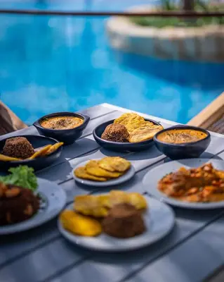 a table topped with plates of food next to a pool at Casa Luna Laguna Beach in Tolú
