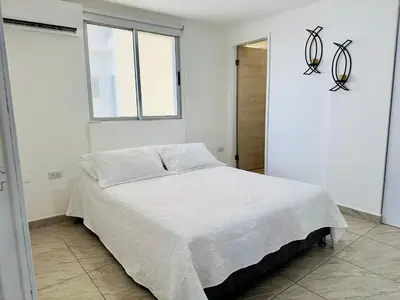 a bedroom with a bed in a white room at Espectacular Ocean view, apartamento de dos cuartos, con vista al mar, en Cartagena de Indias in Cartagena de Indias