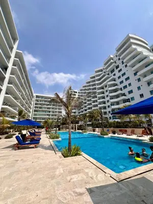 a resort with a swimming pool with people laying in chairs and umbrellas at Apartamento Cartagena Morros Epic con acceso directo a la playa in Cartagena de Indias