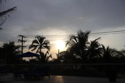 a sunset with palm trees and the sun in the sky at Apartamento Cartagena Morros Epic con acceso directo a la playa in Cartagena de Indias