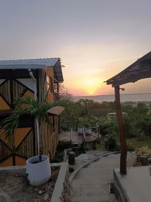 a house with a sunset in the background at Puerta al Mar Ecolodge Glamping in Tubará
