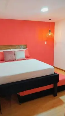 a bedroom with a large bed with a red wall at Hb7 Quadruple Room with shared bathroom in Cartagena de Indias