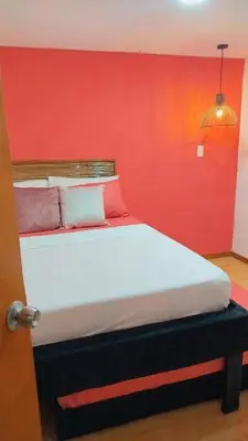 a bed in a room with a red wall at Hb7 Quadruple Room with shared bathroom in Cartagena de Indias