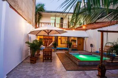 a patio with a pool and an umbrella and chairs at Beach House In La Boquilla Facing the Sea With Air Conditioning and WIFI in Cartagena de Indias